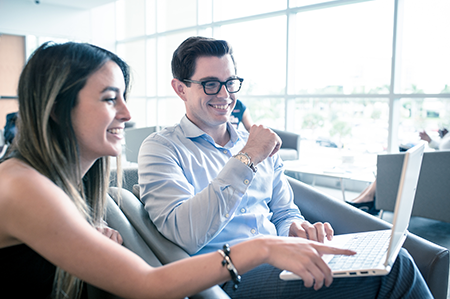 Male and female student looking at a laptop smiling